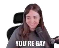 a woman sitting in front of a microphone with the words " you 're gay " on her face