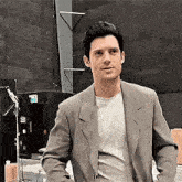 a man in a suit and a white shirt is standing in a room .