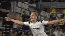 a soccer player is celebrating a goal in front of a banner that says one
