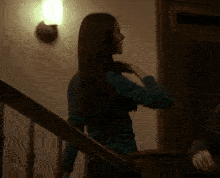 a woman in a green sweater is standing on a set of stairs in a dark room .