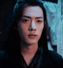 a close up of a young man 's face with long hair .