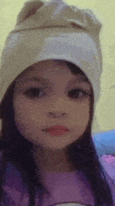 a little girl wearing a hat and a purple shirt