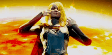 a woman in a supergirl costume is standing in front of a fireball .