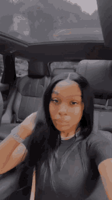a woman is taking a selfie in the back seat of a car with a sunroof .
