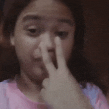 a young woman is making a peace sign with her finger on her nose .