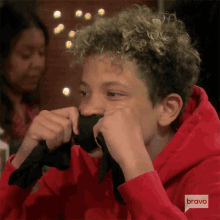 a young boy wearing a red hoodie with bravo written on the bottom left