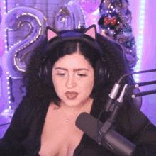 a woman wearing a cat ear headband sits in front of a microphone with the number 20 behind her
