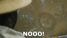a man in a hat is standing in a puddle of water and says nooo !