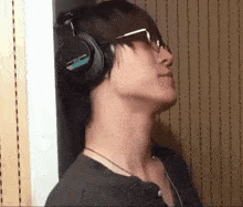 a man wearing headphones and glasses looks up at the sky