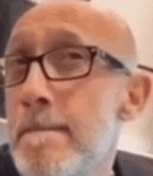 a close up of a man with glasses and a beard making a funny face .
