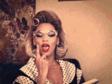 a woman in a polka dot dress is giving the middle finger while holding a book .