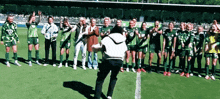 a group of soccer players standing on a field with one wearing a jersey with the number 10