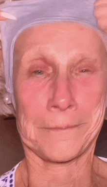 a close up of an older woman 's face with a wig on her head .