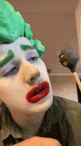 a close up of a person 's face with a green wig and red lips