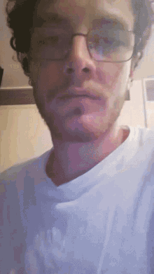 a close up of a man wearing glasses and a white t-shirt