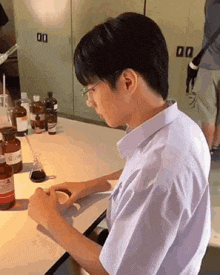 a young man is sitting at a table in a lab with bottles of chemicals .