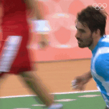 a man in a blue and white shirt is running on a court