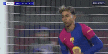 a soccer player wearing a blue and red nike jersey runs towards the goal