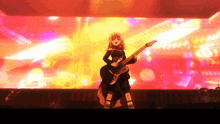 a girl is playing a guitar on a stage in front of a yellow background
