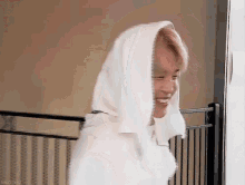 a man wearing a white hoodie is smiling while standing in a room .