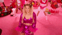 a woman in a pink outfit is standing on a pink floor in front of a group of women in pink outfits .