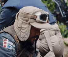 a man wearing a hat and goggles has a patch on his sleeve that says ' fgd ' on it