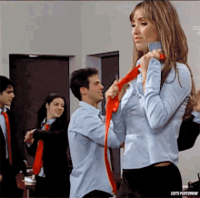 a woman in a blue shirt is being tied to a man in a blue shirt