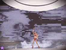 a woman is dancing in front of a large screen