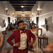 a man in a red suit is dancing in a hallway with the name sanjo_sebi on the bottom
