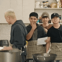 a group of young men are cooking in a kitchen and one of them is wearing a baseball cap with the letter s on it