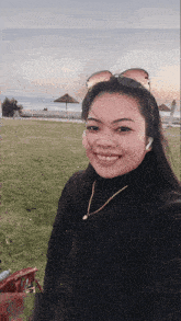 a woman wearing sunglasses and a necklace smiles for a picture