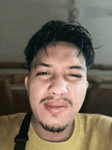 a man with a beard is wearing a yellow sweater and making a funny face