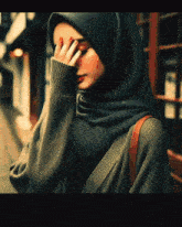 a woman wearing a hijab covering her eyes with her hand