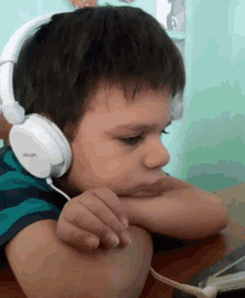 a young boy wearing a pair of white headphones made by philips