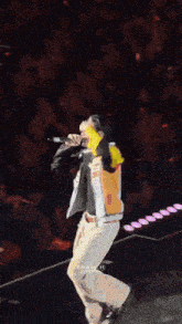 a man in a colorful jacket is singing into a microphone in front of a crowd ..