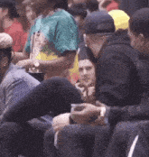 a man wearing a tie dye shirt sits in a crowd of people
