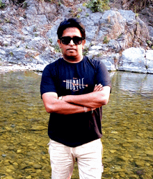 a man wearing a black shirt that says humble hustle stands with his arms crossed