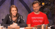 a man and a woman are sitting at a table with a red shirt that says bibliophobia