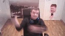 a man is sitting in a chair with his arms outstretched in front of a painting of a man .