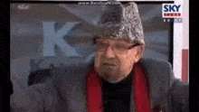 an older man wearing a hat and glasses is talking on a tv show .