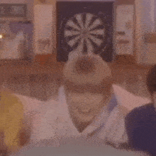 a group of people laying on a bed in front of a dart board .