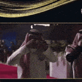 a man in a keffiyeh covering his face with his hand