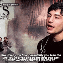 a man in a black shirt is talking to another man in front of a movie poster .