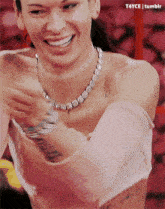 a woman wearing a choker necklace and a pink top is smiling and laughing .