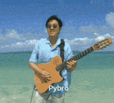 a man is playing a guitar on the beach and the name pybro is below him