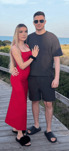 a man and a woman are posing for a picture on a wooden walkway