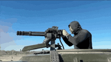 a man in a hooded sweatshirt is holding a machine gun