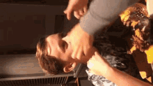 a man is being slapped in the face by another man while sitting at a table with a hamburger .