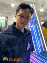 a man wearing glasses stands in front of a lc sign