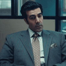 a man in a suit and tie with a checkered pocket square
